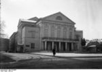 A grayscale image of a small museum with a statue of two men in front.