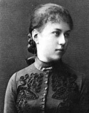 Young woman facing right, wearing high-necked, embroidered dress