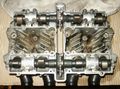 Overhead view of an air cooled cylinder head from a سوزوكي GS550 showing dual camshafts, drive sprockets and cooling fins.