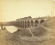 Photograph (1855) of the Dapoorie Viaduct, Bombay. The viaduct, shown with a train steaming across it, was completed in 1853 and linked Bombay Island with Thane on the mainland.