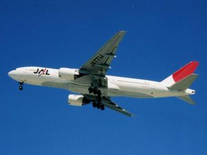 A under-carriage view of a Boeing 777-200 aircraft in mid air, with blue sky in the background