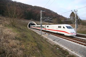 White electric train with red cheatline emerging from tunnel in the countryside