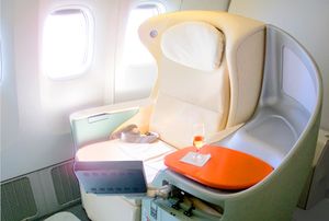 A cream coloured seat with a glass of champagne on the right and two unshaded windows on the left