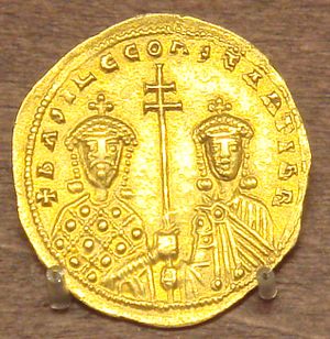 A photograph of a gold coin depicting two crowned figures, both grasping a double-barred patriarchal cross between them