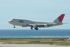 A Boeing 747-400D aircraft in mid air during landing with the view of the taxiway on the foreground and the sea and sky on the background