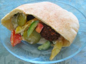 A pita filled with vegetables and fritters on a plate