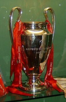 A silver trophy with red ribbons on it