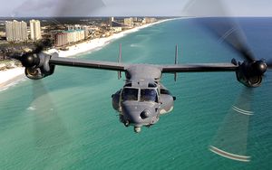 A front view of a U.S. Air Force CV-22 with its rotors facing forward flying over the Emerald Coast of Florida.