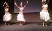 colour photo of three female dancers wearing white skirts, bikini tops and headresses, all made of chicken feathers,