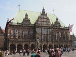 A dark stone gothic building in a paved town square.