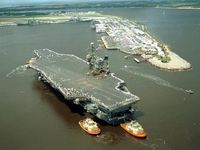 Tugboats placing the USS John F. Kennedy (CV 67) into port