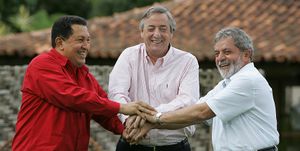 Three smiling, casually-dressed men, clasping hands