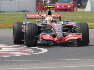 A silver Formula One car driving around a corner.