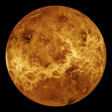 A false-colour image of Venus: ribbons of lighter colour stretch haphazardly across the surface. Plainer areas of more even colouration lie between.