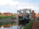 Two medium-sized boats float in front of a large iron structure.