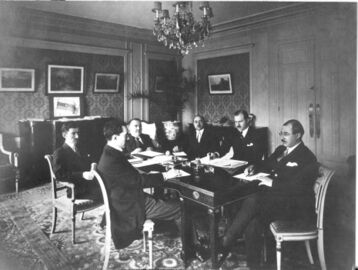 Azerbaijani delegation in Paris at the Claridge Hotel during the Paris Peace Conference, 1919. The tricolour flag of the ADR is visible in the background, on the chest of drawers.