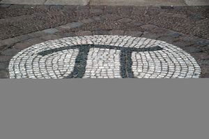A photograph of the Greek letter pi, created as a large stone mosaic embedded in the ground.