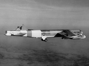 Black-and-white photo of a B-52 with its vertical stabilizer sheared off, but still flying.
