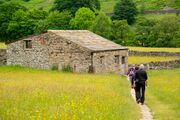 Hikers at a traditional field barn in Muker, North Yorkshire