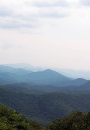 Green tree covered mountains turn blue as the progress toward the horizon.