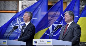 Two men in business suits stand at white podiums in front of blue and white NATO flags and blue and gold Ukrainian flags.