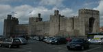 A medieval-style castle with a parking lot in the foreground.