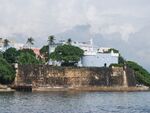 A blue fortress and stone walls above a bay