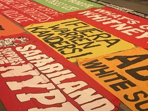 image of banners on floor of museum lobby, reading "Fuera Warren Kanders" and "Safariland Supports the NYPD"