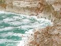 A rough Dead Sea, with salt deposits on cliffs