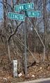 A sign along with a stone marking the border between Lexington, Massachusetts and Burlington, Massachusetts on a local road.