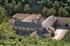 In a wooded valley is a gaunt stone church with small windows and a square stone belfry. It is surrounded by ancient buildings arranged around courtyards, and a lavender garden.