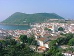 Coastal town with white houses and churches with red roofs.