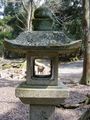 Stone lantern leading up to shrine framing a Nara Park deer