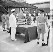 A Japanese officer surrenders his sword to a British Lieutenant in a ceremony in Saigon.